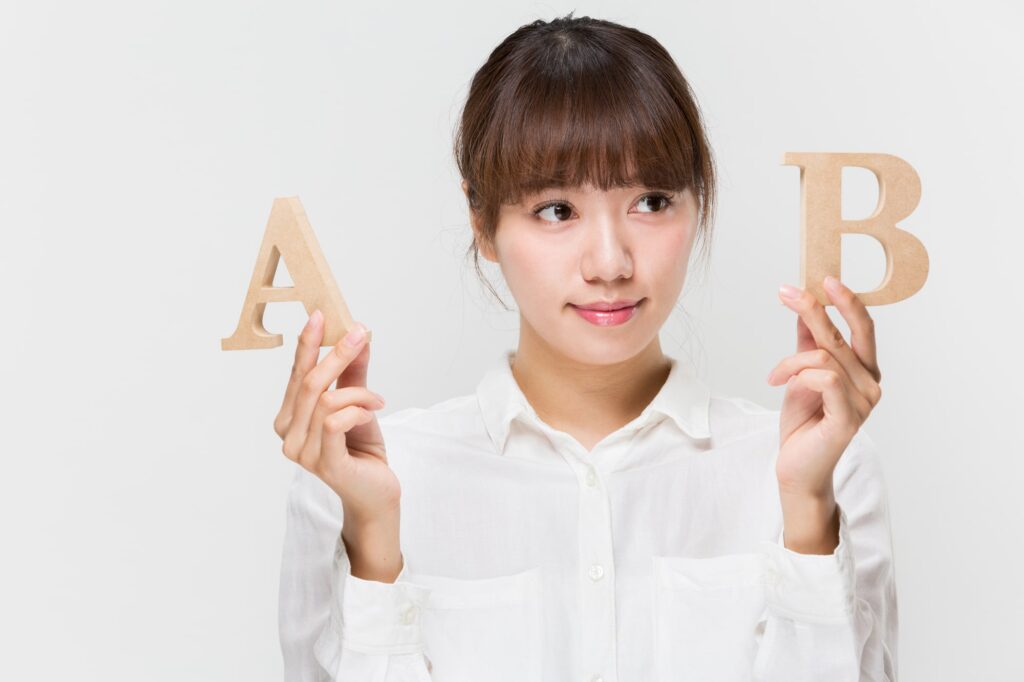 AとBのブロックを手に持ち、悩んでいる女性