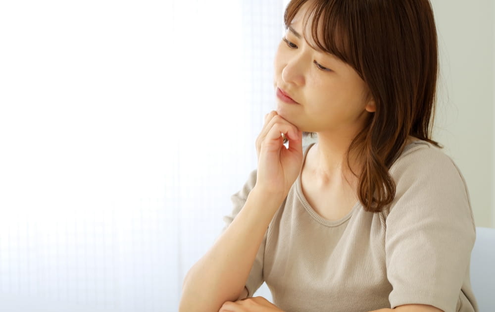 顎に手を当てて考えている女性