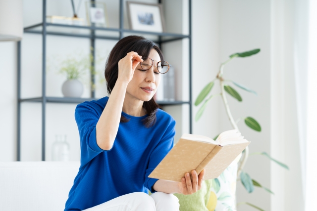 見えづらそうにしている読書中の女性