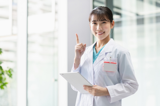 白衣を着た女性医師がタブレットを持ち指差し