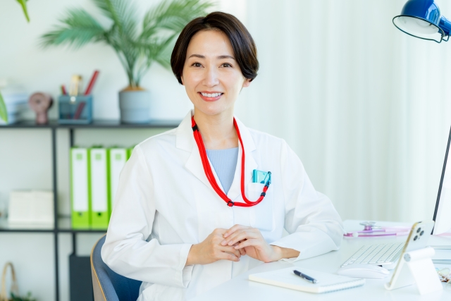 診察室で白衣を着て座る女性医師