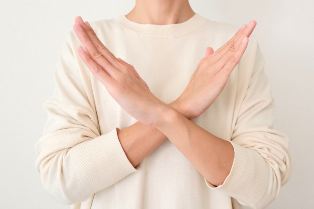 腕を組んでバツ印を作る女