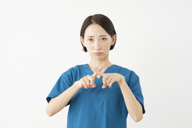 腕でバツ印を作る医療従事者