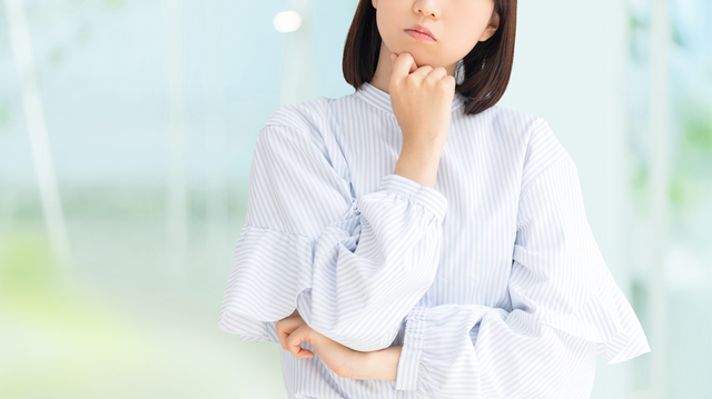 顎に手を当てて考えごとをする女性