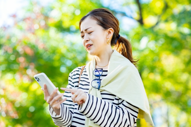 困った表情でスマホを見る女性