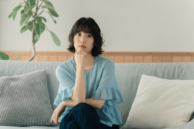 ソファに座って考える女性